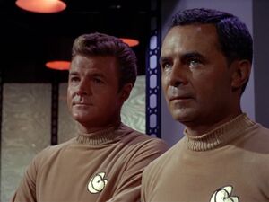 Two members of the Starfleet Auxiliary in the 2260s, wearing the distinctive Spacecraft Duty Insignia and an older uniform than their Starfleet counterparts of that time period.